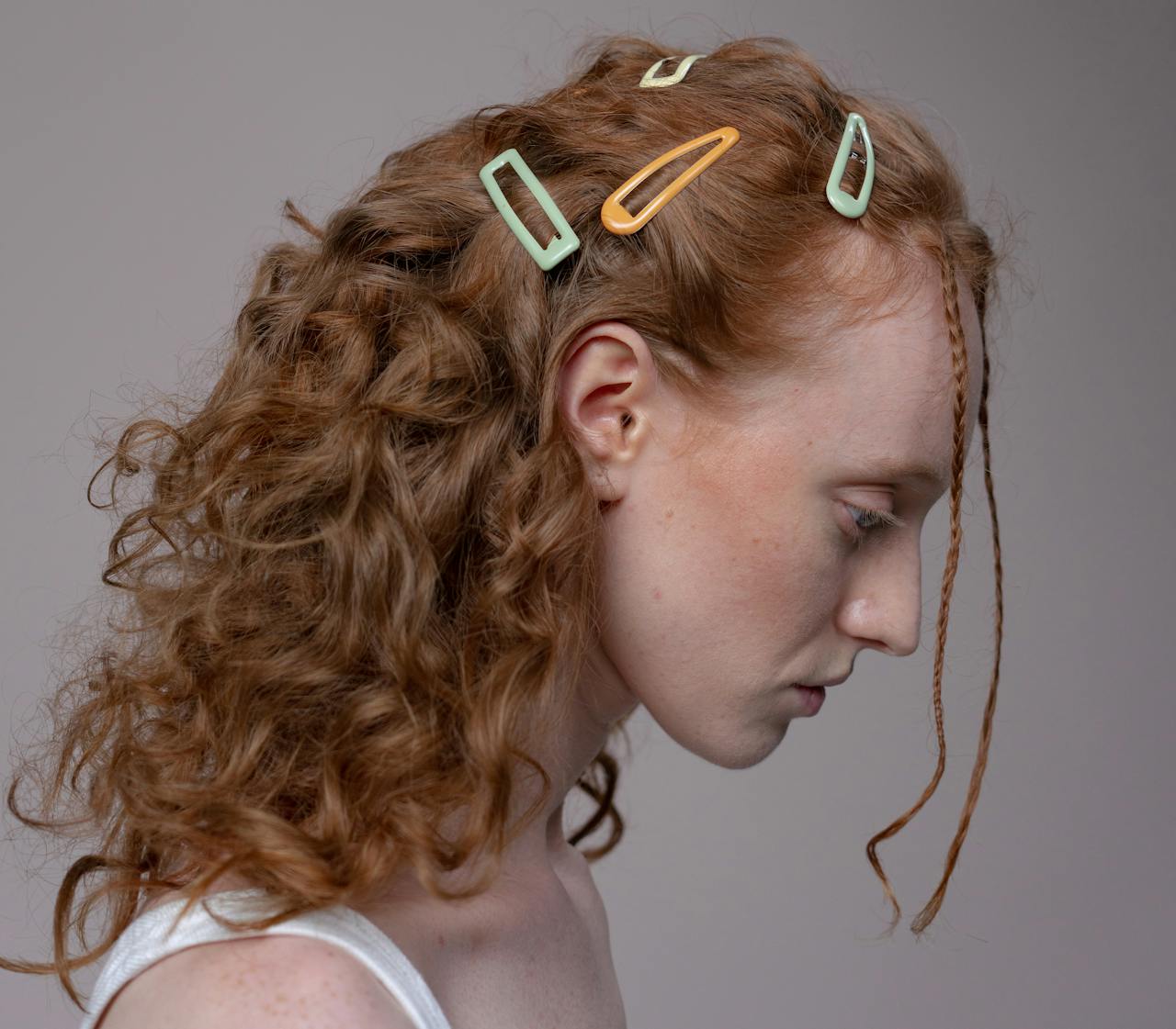 Close-up profile of a redheaded woman with stylish hair clips and curly hair.